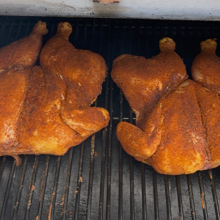 Two chickens being grilled on a barbecue grill.