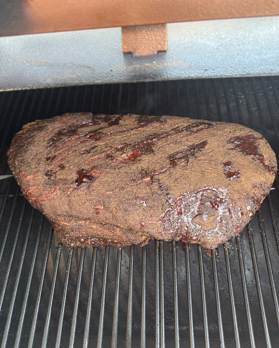 Pork Butt smoking on grill with seasoned bark during backyard barbecue cookout for Barracks BBQ brand image