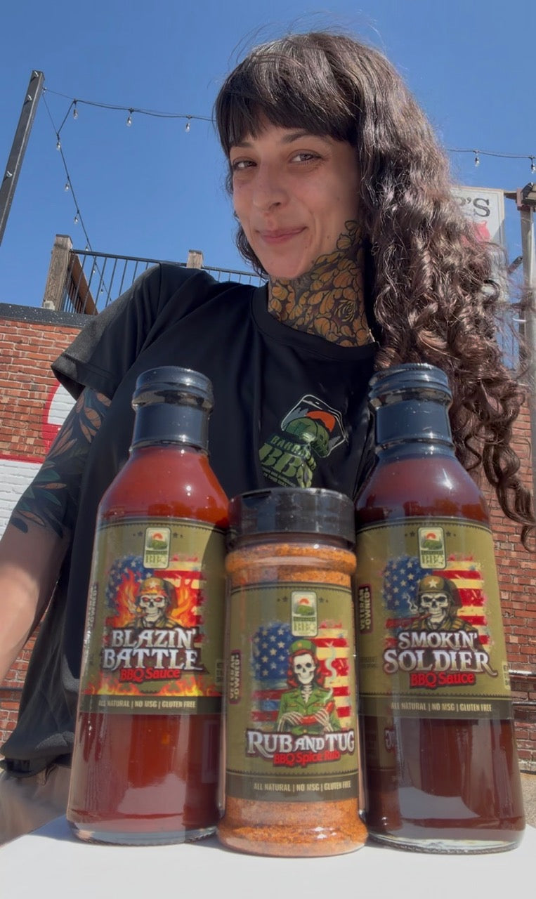 Person holding three bottles of Blazin' Battle and Smokin' Soldier hot sauce with a tattooed arm.